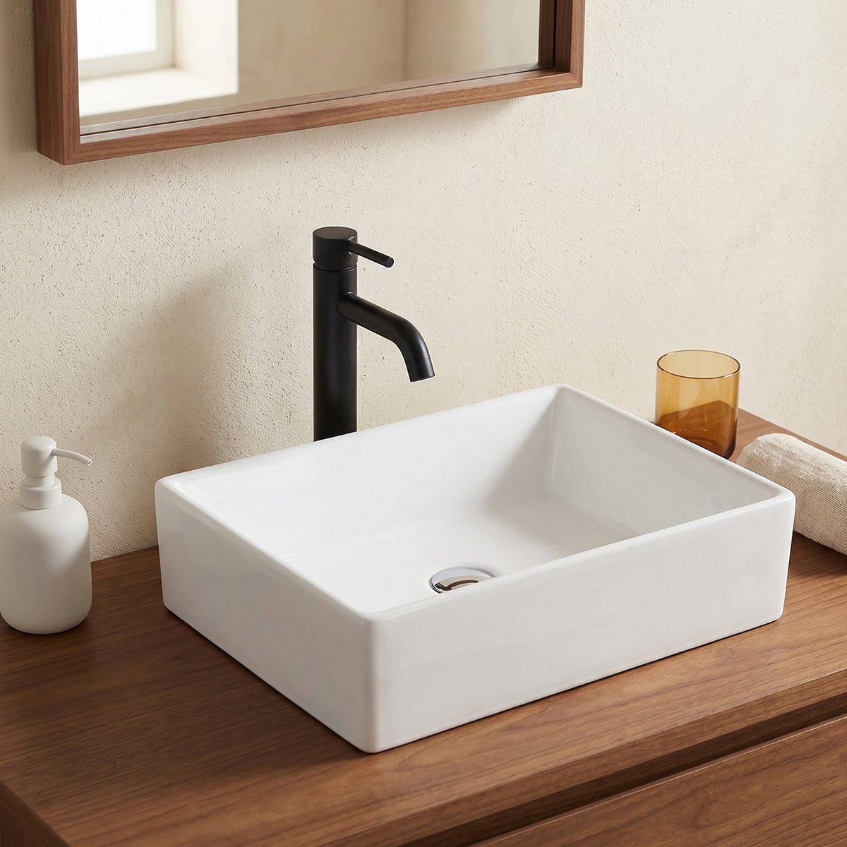 Above-counter ceramic basin on a wood vanity with a black deck-mounted faucet and framed mirror