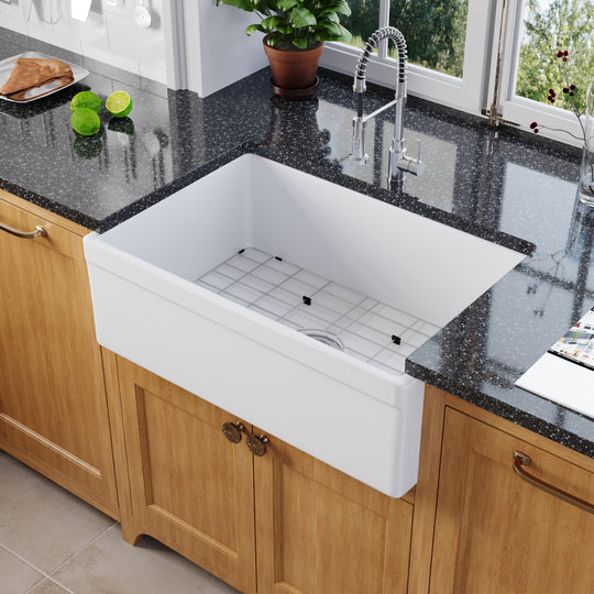 White fireclay apron-front farmhouse sink installed in a wood-cabinet kitchen — SANIKB SNT3020H