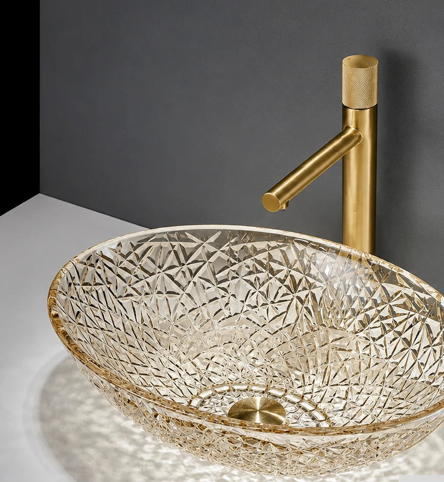 Champagne crystal-cut glass vessel sink with gold faucet on a styled vanity