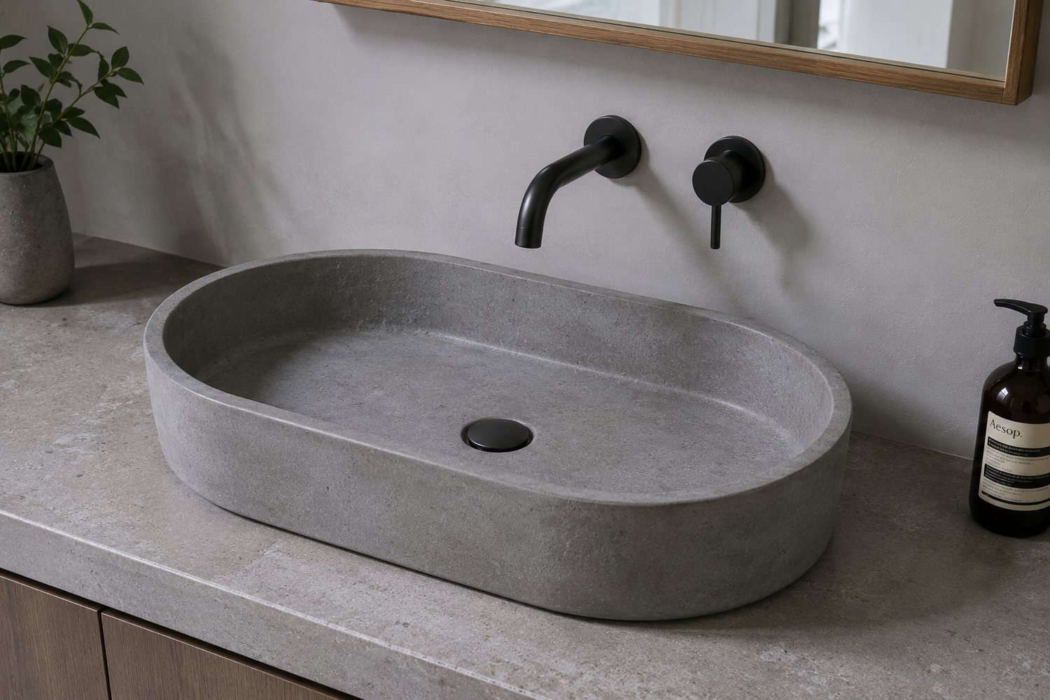 Oval gray concrete sink with wall-mounted black faucet on a modern bathroom vanity.