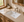 Rectangular undermount ceramic basin installed in a beige stone vanity countertop with a brushed nickel widespread faucet