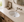 White ceramic undermount vanity sink installed in a light stone vanity top with a wall-mounted faucet