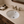 White ceramic undermount bathroom sink installed in a beige stone countertop with a brushed bronze faucet