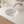 Ceramic undermount vanity sink installed in a light stone countertop with a wall-mounted faucet