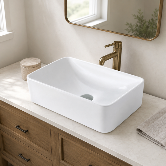 White narrow rectangular ceramic vessel sink on a wood vanity with a tall gold-tone faucet and a framed mirror