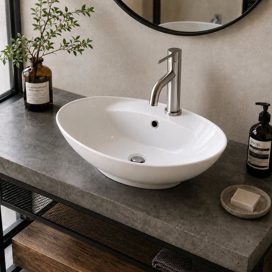 Oval ceramic vessel sink with faucet deck installed in a styled bathroom — lifestyle scene, SANIKB SN149.