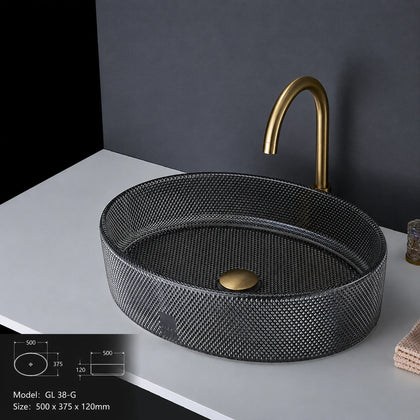 Charcoal grey faceted glass vessel sink with gold faucet, oval 500mm bowl