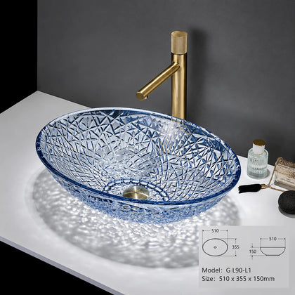 Clear blue-rimmed faceted glass vessel sink with gold faucet, oval bowl
